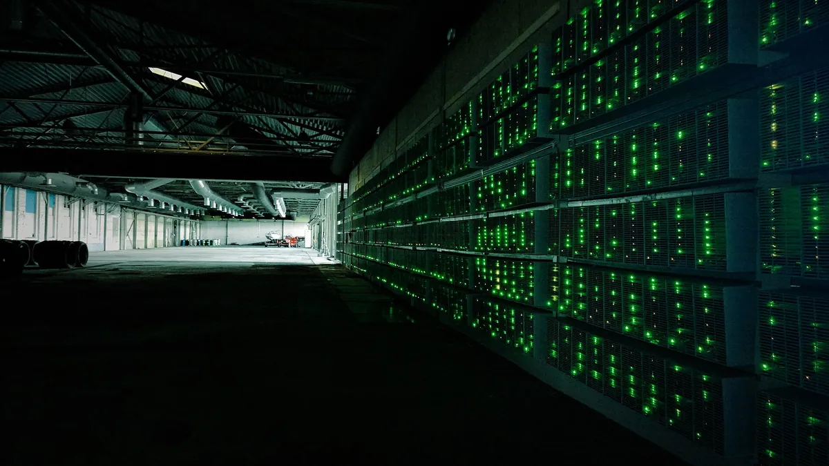 Rows of bitcoin mining machines with green lights in a large mining farm