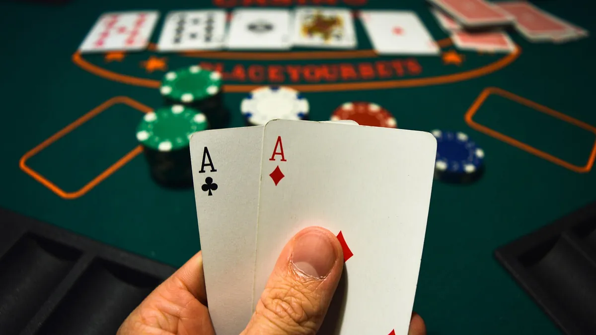 Hand holding a pair of aces over a poker table with chips